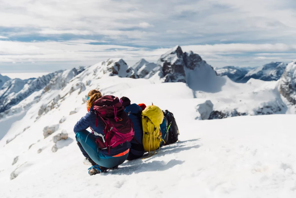 back-view-of-hiking-couple-sitting-in-the-snow-enjoying-the-view-of-winter-alps-from-high-up